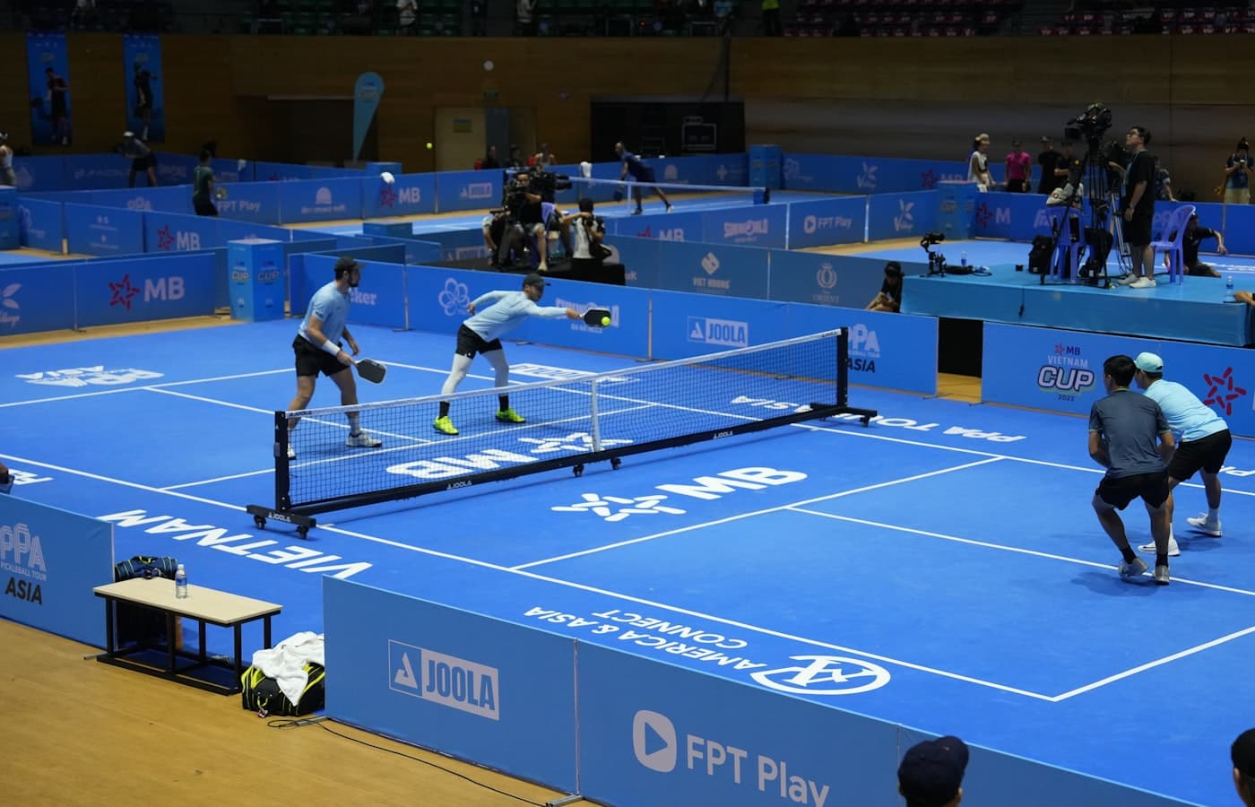 Indoor sports hall with pickleball nets set up under bright ceiling lights
