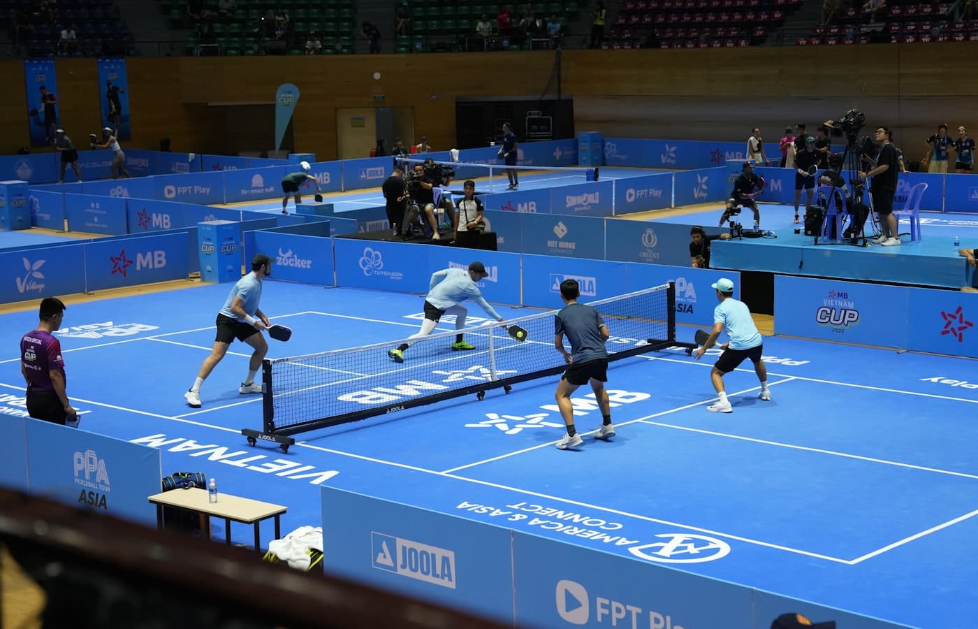 Pickleball paddle and ball resting on the non-volley zone line of an indoor court
